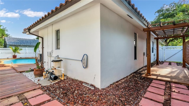 view of side of property with a pool side deck and a pergola