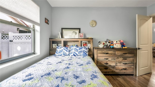 bedroom with multiple windows and dark wood-type flooring