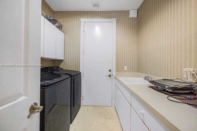 washroom featuring light tile patterned flooring, sink, cabinets, and washing machine and dryer