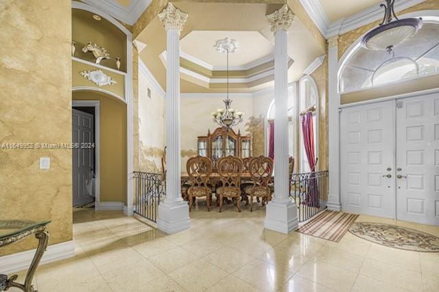 foyer with tile patterned flooring, ornamental molding, an inviting chandelier, and ornate columns