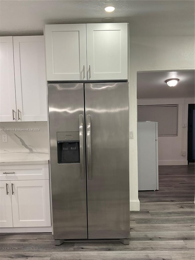 kitchen with white refrigerator, hardwood / wood-style flooring, white cabinetry, and stainless steel refrigerator with ice dispenser