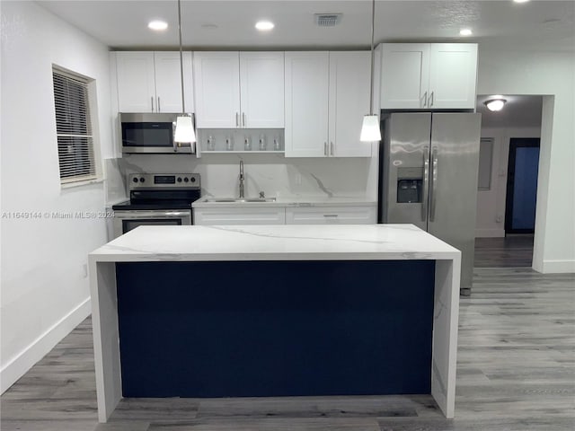 kitchen with a center island, stainless steel appliances, white cabinets, and light hardwood / wood-style floors