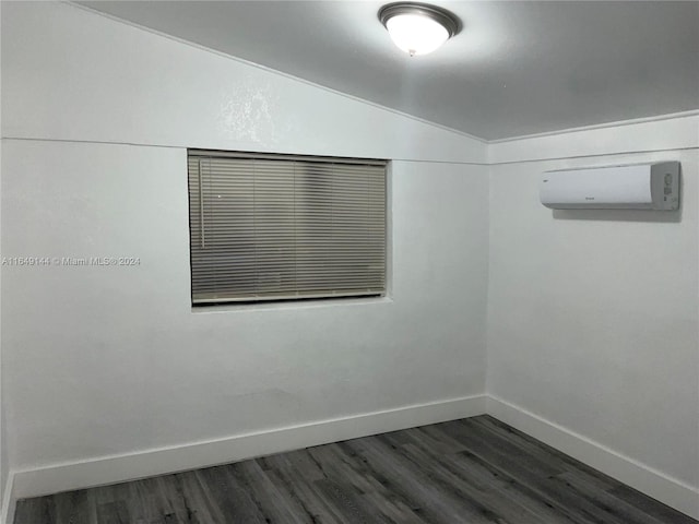 unfurnished room featuring a wall unit AC and dark hardwood / wood-style floors