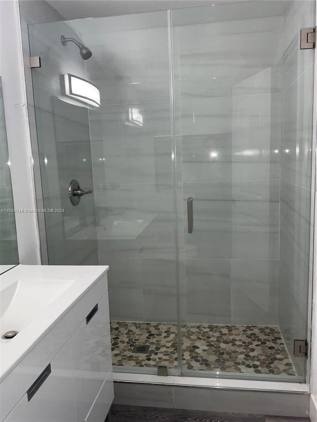 bathroom featuring a shower with door and vanity