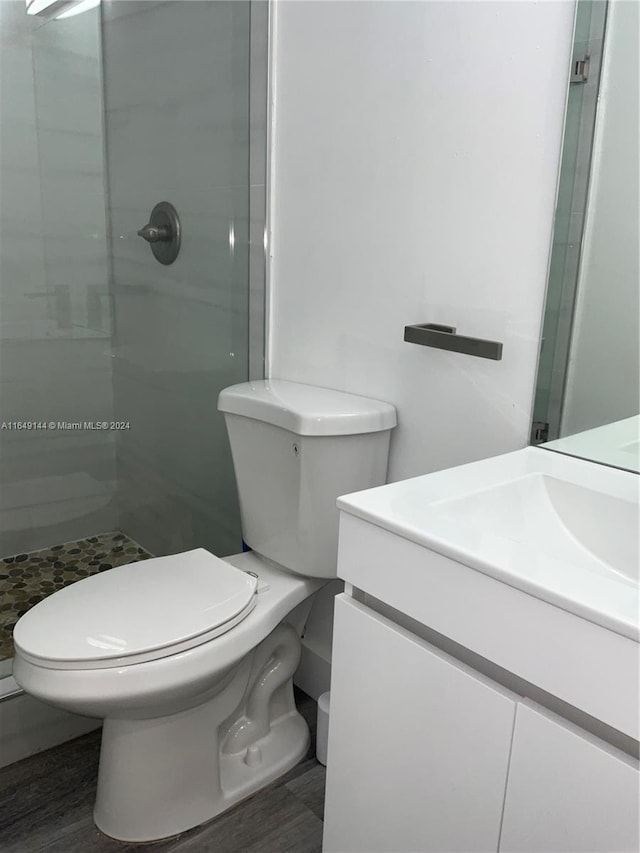 bathroom featuring a shower with shower door, toilet, and vanity