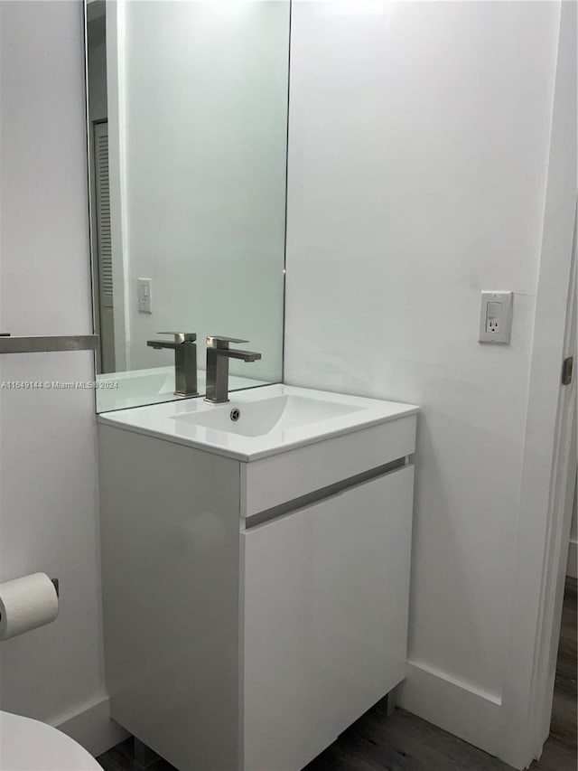 bathroom with toilet, hardwood / wood-style flooring, and vanity