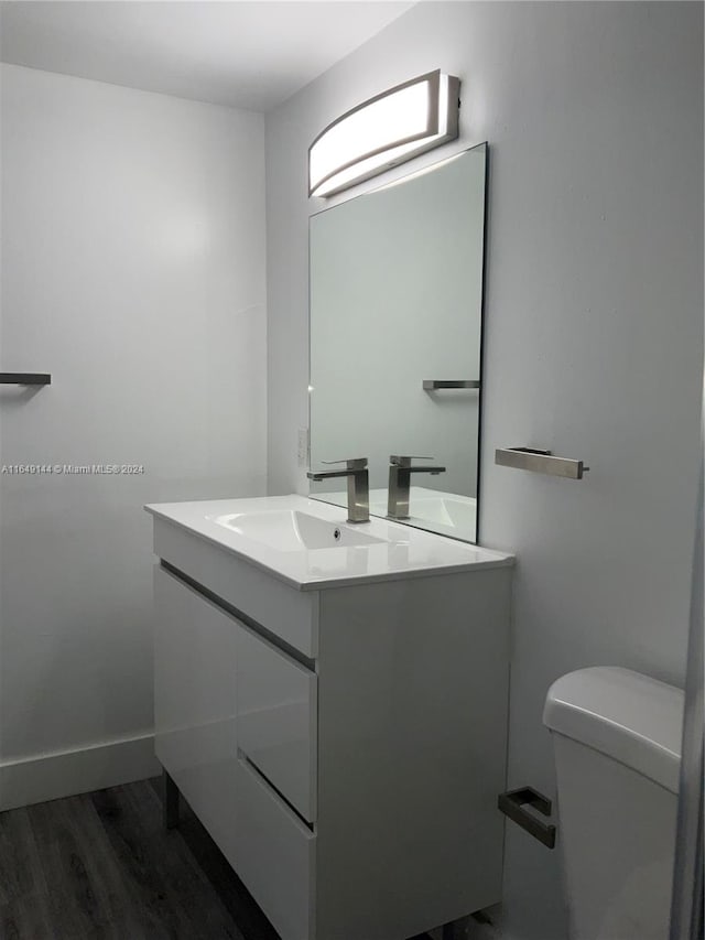 bathroom featuring wood-type flooring, toilet, and vanity