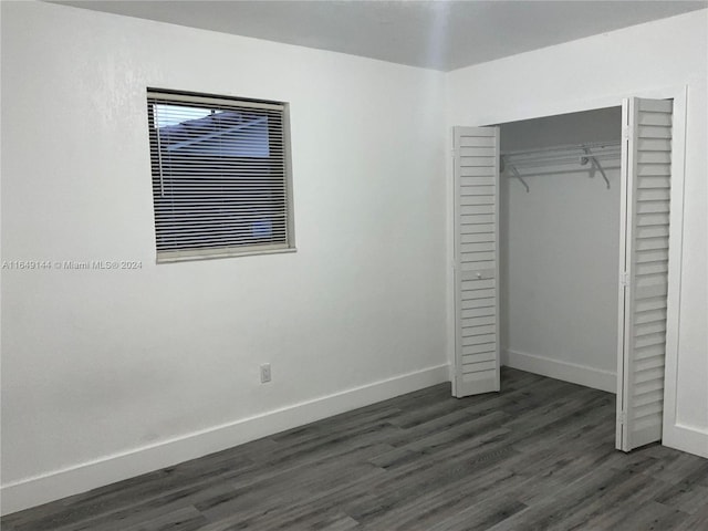 unfurnished bedroom with dark hardwood / wood-style floors and a closet