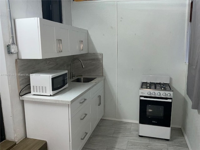 kitchen featuring sink, white appliances, white cabinets, and light tile patterned flooring