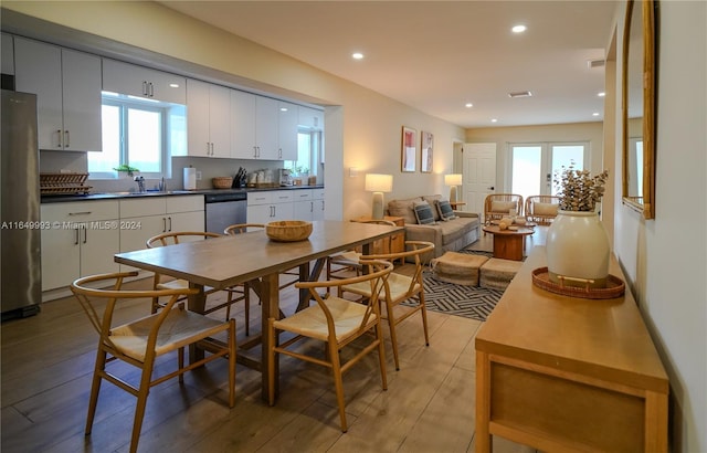 kitchen with appliances with stainless steel finishes, white cabinetry, sink, and light hardwood / wood-style flooring