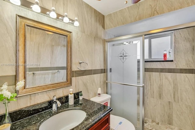 bathroom featuring vanity, toilet, an enclosed shower, and tile walls