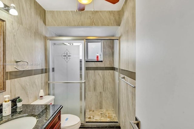 bathroom with vanity, toilet, a shower with shower door, and ceiling fan