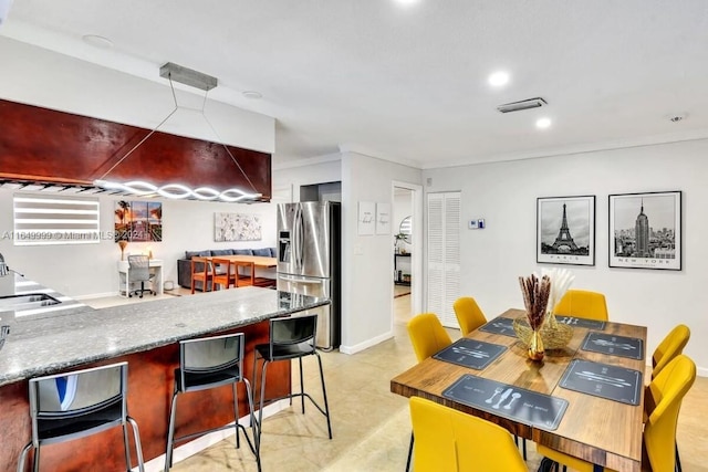 kitchen featuring crown molding, stainless steel fridge, a kitchen breakfast bar, kitchen peninsula, and sink