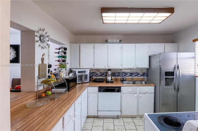 kitchen with light tile patterned floors, appliances with stainless steel finishes, tasteful backsplash, sink, and white cabinets