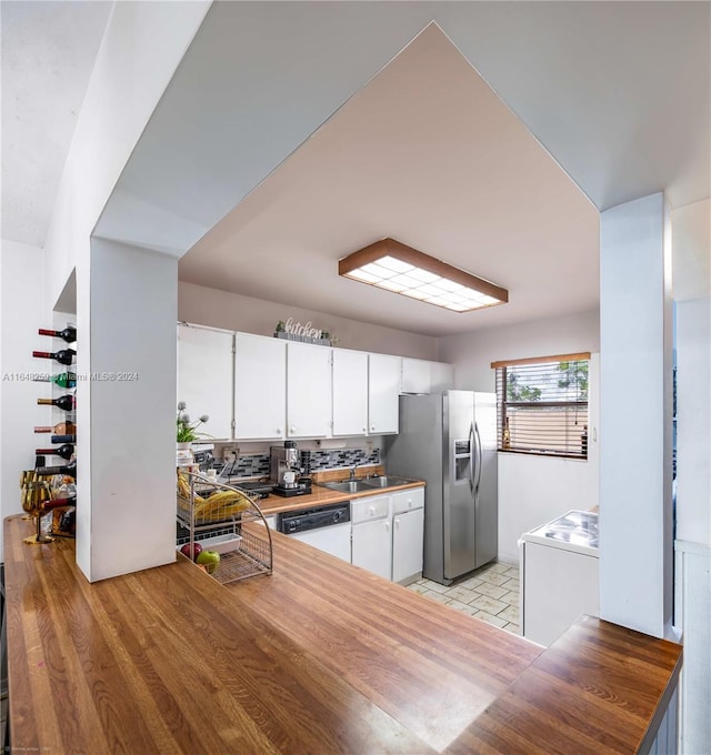 kitchen with white dishwasher, light tile patterned floors, decorative backsplash, and white cabinets