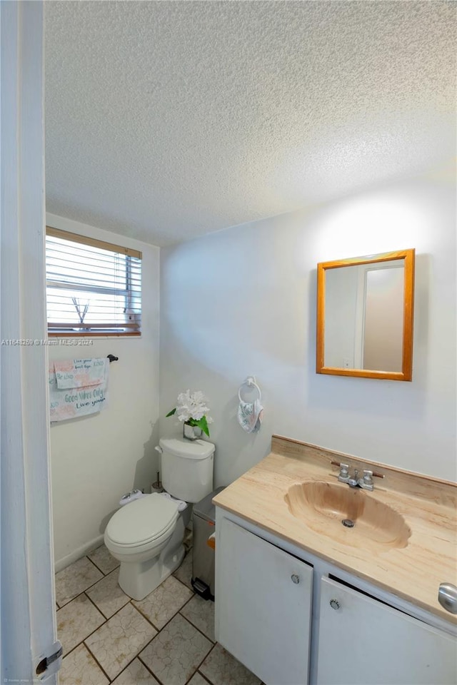 bathroom featuring tile patterned flooring, toilet, a textured ceiling, and vanity