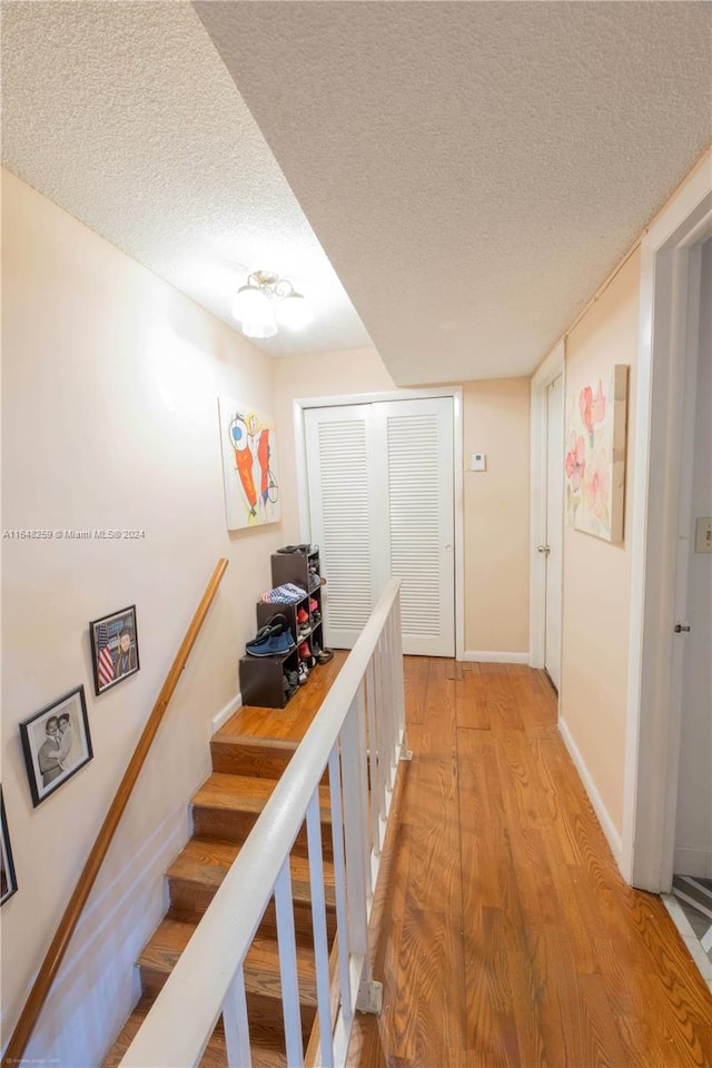 hall with light wood-type flooring and a textured ceiling