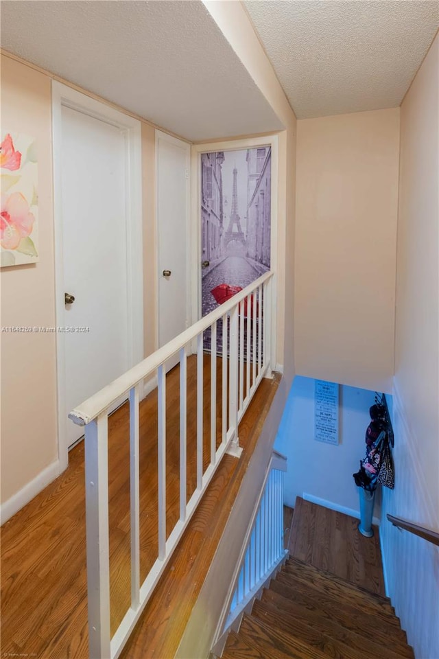 staircase with a textured ceiling and hardwood / wood-style floors