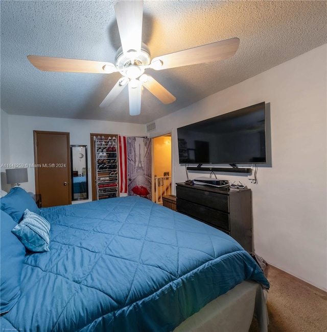 bedroom with a closet, a textured ceiling, ceiling fan, and carpet