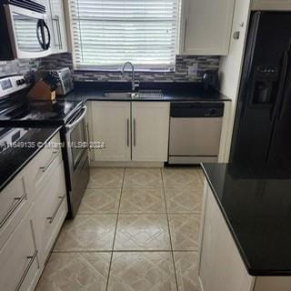 kitchen with backsplash, light tile patterned floors, stainless steel appliances, white cabinetry, and sink