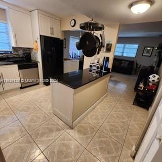 kitchen featuring dishwasher, light tile patterned floors, white cabinets, and black fridge