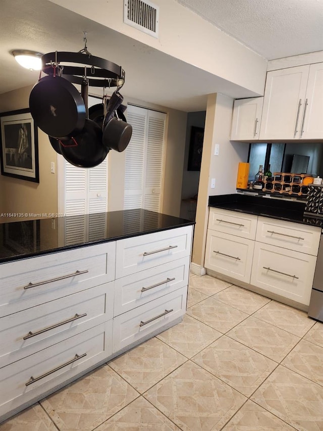 kitchen featuring a textured ceiling, white cabinetry, and light tile patterned flooring