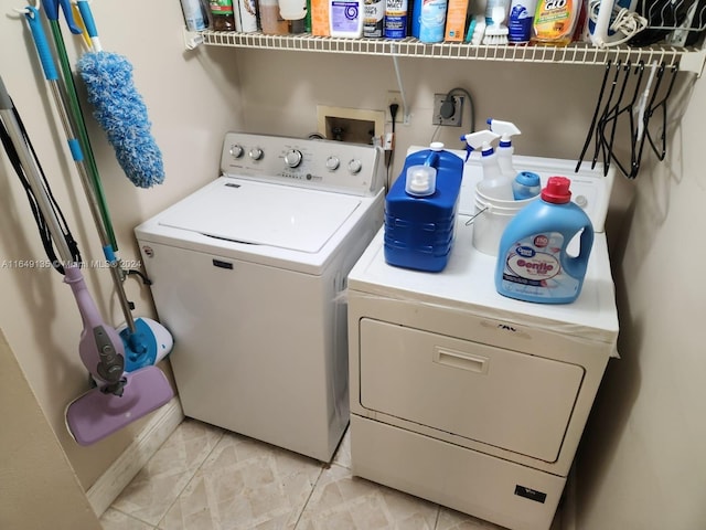 clothes washing area featuring washer and dryer and light tile patterned flooring