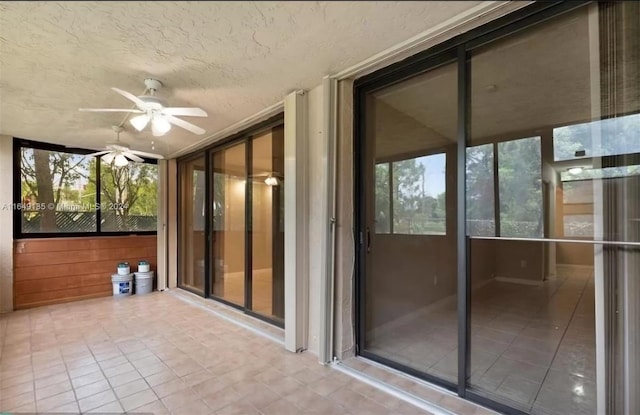 unfurnished sunroom with ceiling fan