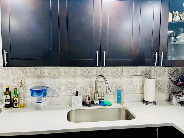 kitchen with light stone counters, backsplash, and sink