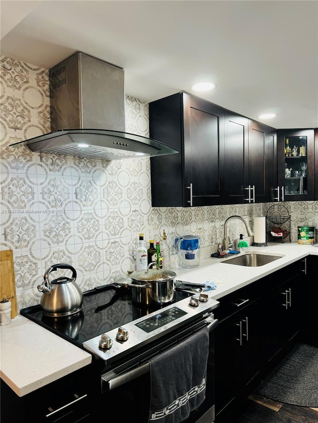 kitchen with hardwood / wood-style flooring, sink, stainless steel range with electric cooktop, wall chimney exhaust hood, and decorative backsplash