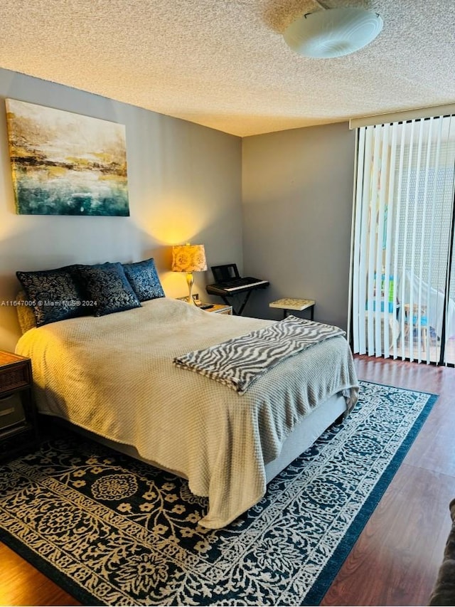 bedroom featuring multiple windows, a textured ceiling, and hardwood / wood-style flooring