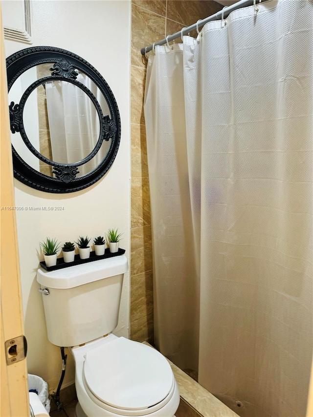 bathroom featuring a shower with curtain and toilet