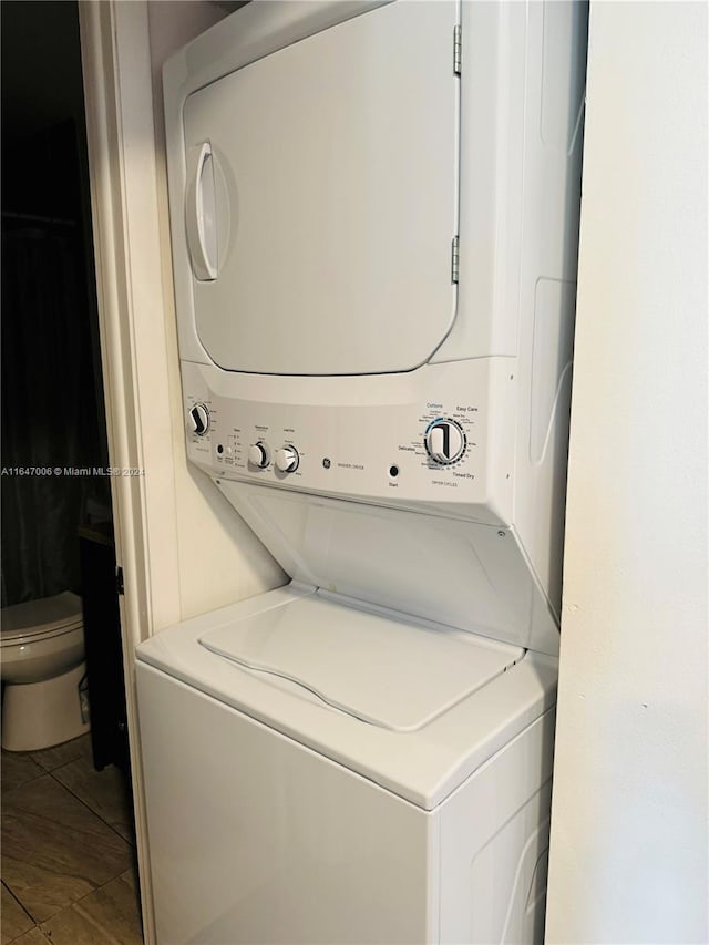 laundry room featuring tile patterned flooring and stacked washer and clothes dryer