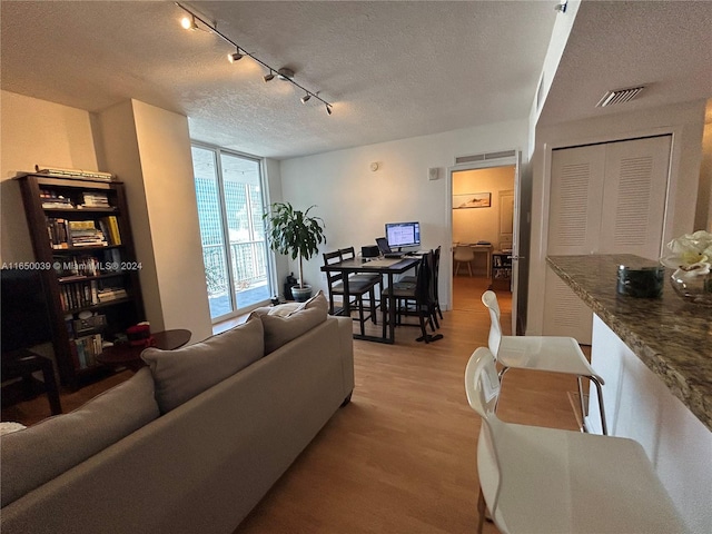 living room with a textured ceiling, rail lighting, and hardwood / wood-style floors