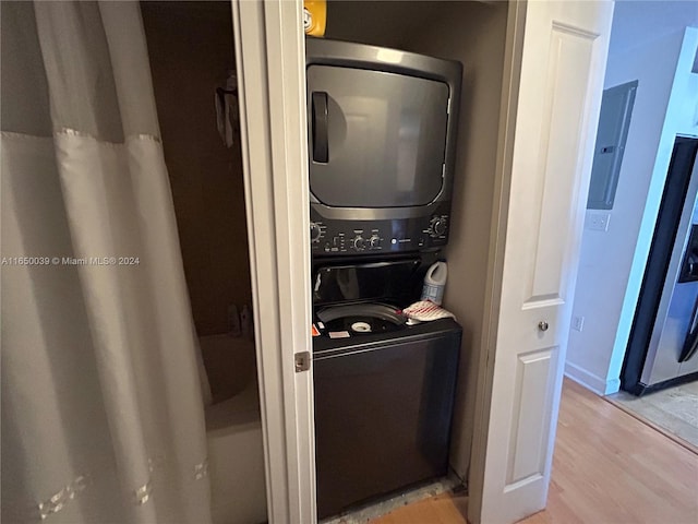 laundry area featuring electric panel, stacked washer and clothes dryer, and light hardwood / wood-style floors