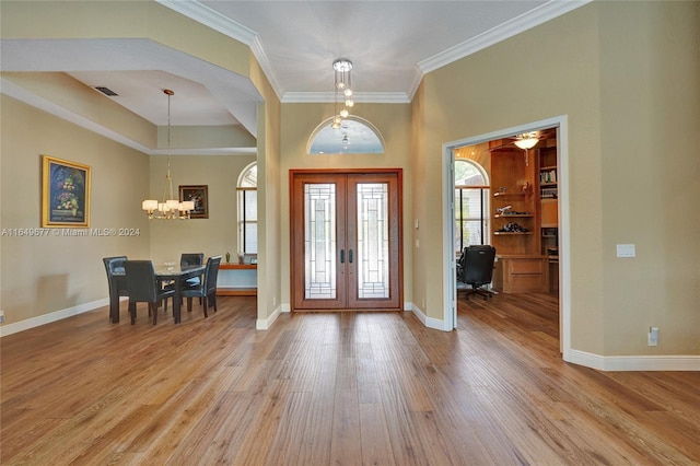 foyer entrance featuring light wood-type flooring, french doors, crown molding, and a chandelier