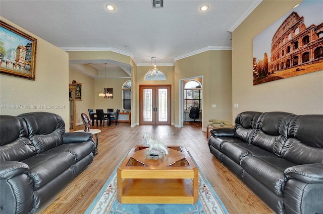 living room featuring light wood-type flooring, french doors, ornamental molding, and a textured ceiling