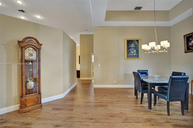 dining room featuring a tray ceiling, wood-type flooring, and a notable chandelier