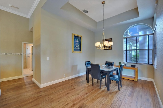 dining room featuring ornamental molding, light hardwood / wood-style flooring, an inviting chandelier, and a tray ceiling