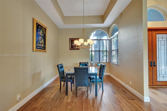 dining room with a raised ceiling, a notable chandelier, and wood-type flooring