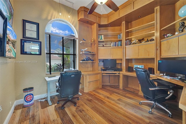 office area with light wood-type flooring, ceiling fan, and a towering ceiling