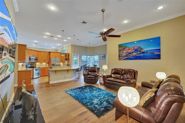 living room with light hardwood / wood-style flooring, ceiling fan, and ornamental molding