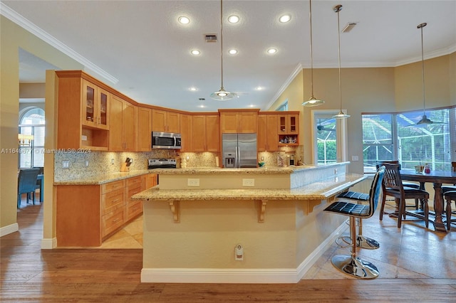 kitchen with decorative light fixtures, stainless steel appliances, a center island, decorative backsplash, and a breakfast bar