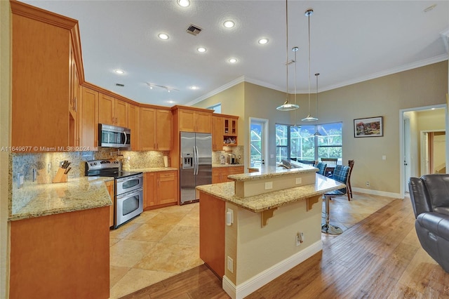 kitchen with a breakfast bar area, light hardwood / wood-style flooring, appliances with stainless steel finishes, hanging light fixtures, and decorative backsplash