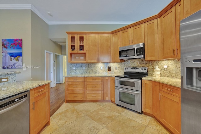 kitchen with appliances with stainless steel finishes, light stone counters, decorative backsplash, and ornamental molding