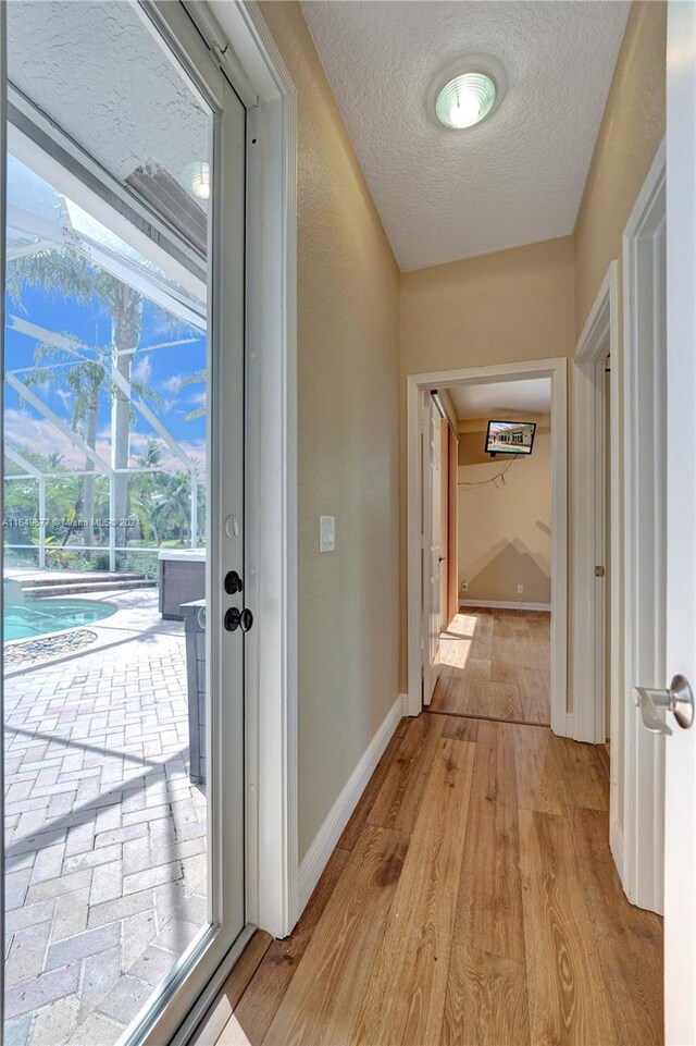 hallway with a textured ceiling and light wood-type flooring