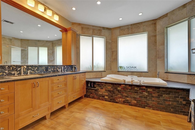 bathroom featuring hardwood / wood-style floors, tile walls, independent shower and bath, tasteful backsplash, and vanity