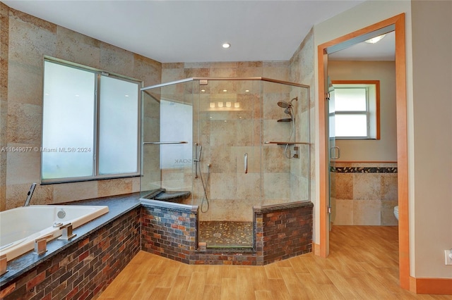 bathroom featuring plus walk in shower, hardwood / wood-style floors, and toilet