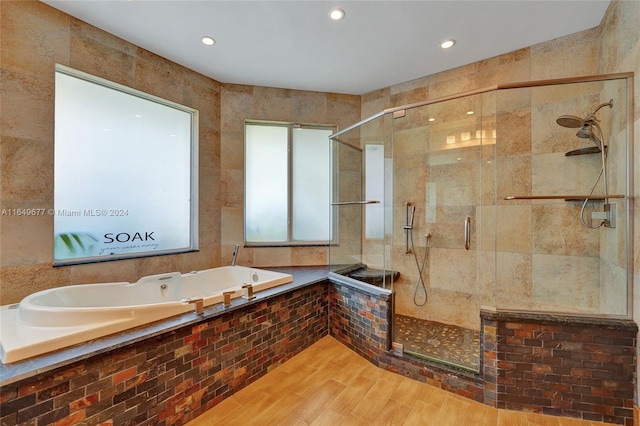 bathroom with tile walls, wood-type flooring, and shower with separate bathtub