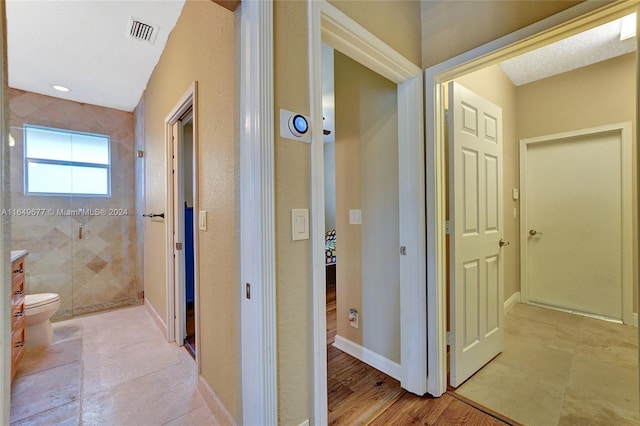 bathroom with vanity, toilet, hardwood / wood-style flooring, and tiled shower